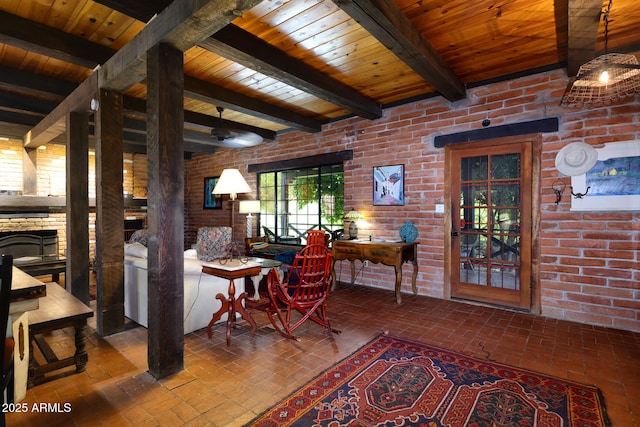 interior space featuring beam ceiling, wood ceiling, a fireplace, brick floor, and brick wall