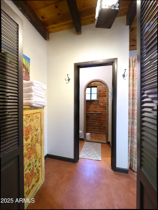 interior space featuring baseboards, wooden ceiling, and beam ceiling