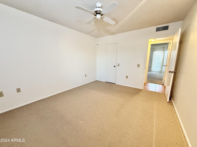 unfurnished bedroom featuring carpet, a textured ceiling, and ceiling fan