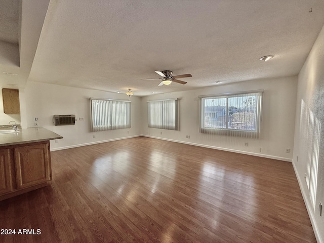 unfurnished living room featuring dark hardwood / wood-style flooring, ceiling fan, sink, and a textured ceiling