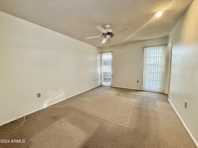 spare room with a textured ceiling, carpet floors, a wealth of natural light, and ceiling fan