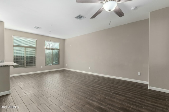 empty room featuring dark hardwood / wood-style floors and ceiling fan with notable chandelier