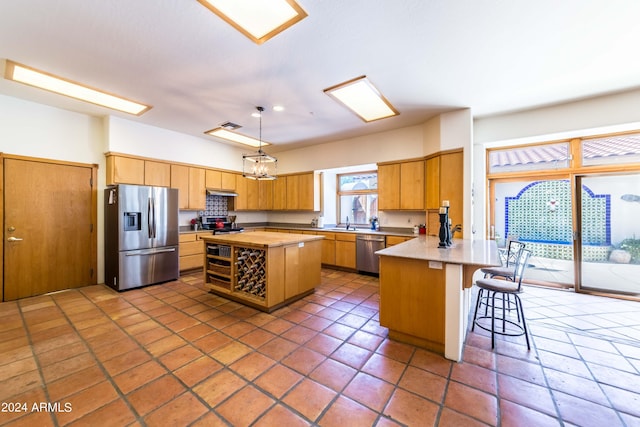 kitchen featuring a center island, sink, hanging light fixtures, a kitchen bar, and stainless steel appliances