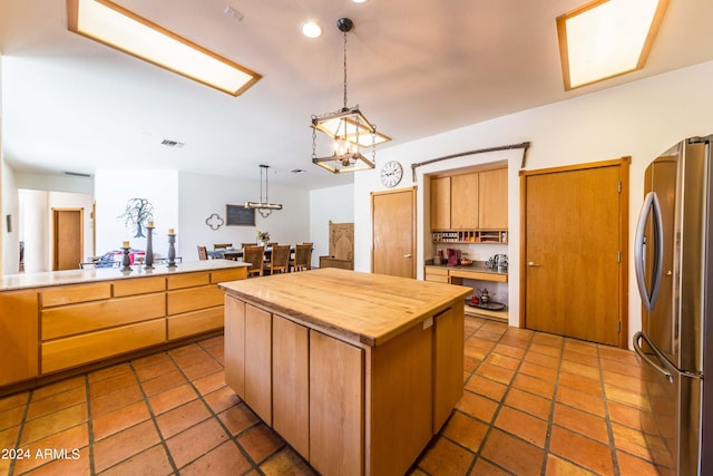 kitchen with butcher block counters, a center island, stainless steel fridge, a chandelier, and pendant lighting