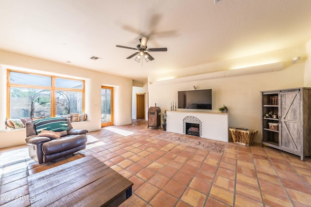 living room featuring a fireplace, light tile patterned floors, and ceiling fan