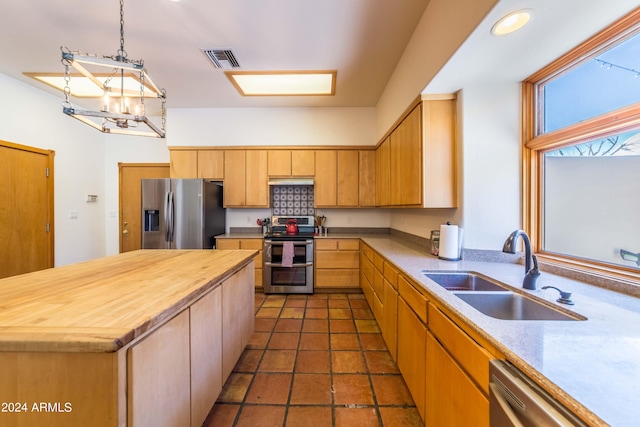 kitchen featuring an inviting chandelier, sink, appliances with stainless steel finishes, decorative light fixtures, and a kitchen island