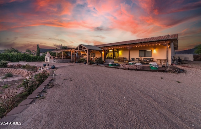 back house at dusk with a patio area and a pergola