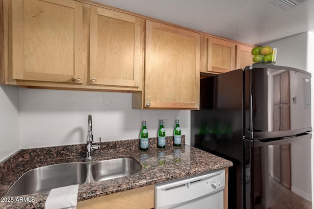 kitchen with sink, dark stone counters, white dishwasher, black fridge, and light brown cabinets