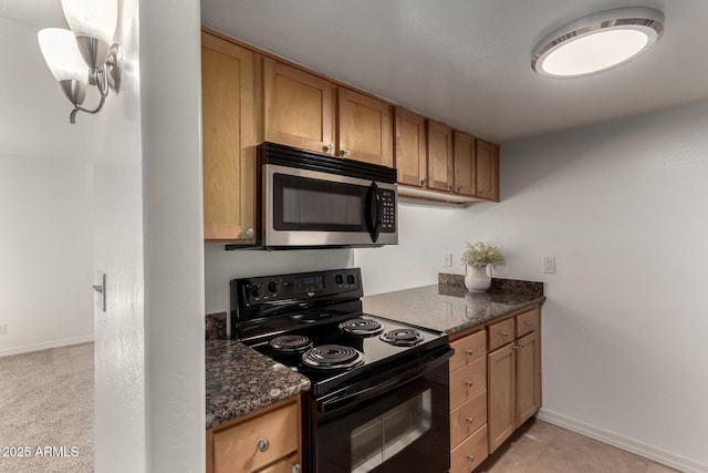 kitchen featuring pendant lighting, black range with electric cooktop, and dark stone counters