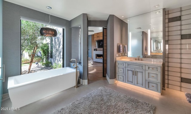 full bath featuring a large fireplace, visible vents, tile patterned flooring, vanity, and a freestanding tub