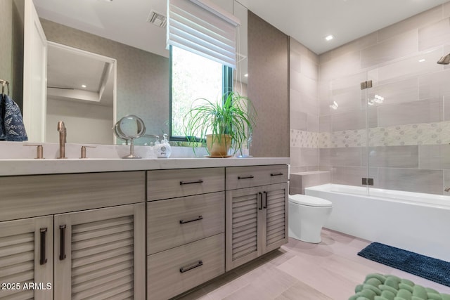 full bathroom with tile patterned flooring, toilet, bath / shower combo with glass door, vanity, and visible vents