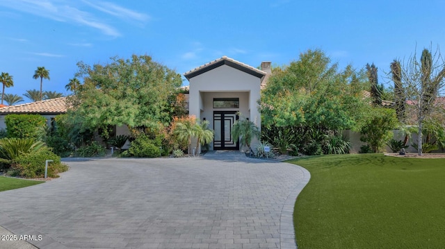 view of front of home with a tile roof, fence, a front lawn, and stucco siding