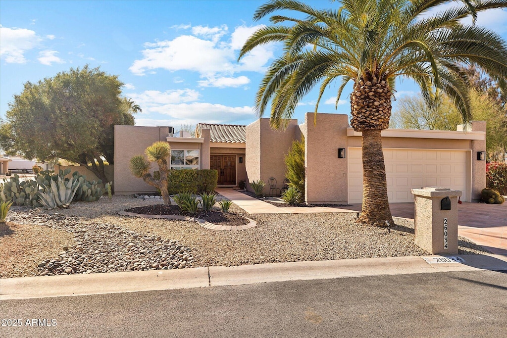 pueblo revival-style home featuring concrete driveway, an attached garage, and stucco siding