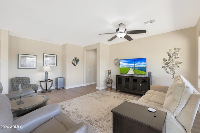 living room with baseboards, visible vents, wood finished floors, and a ceiling fan
