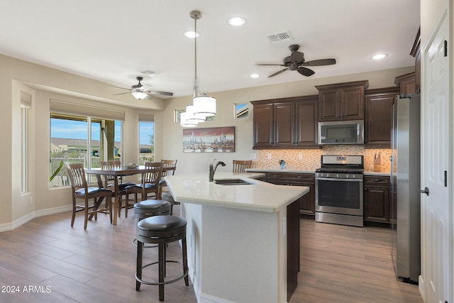 kitchen featuring hardwood / wood-style flooring, appliances with stainless steel finishes, sink, and pendant lighting