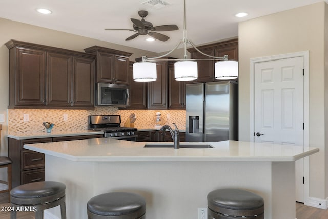 kitchen with a large island with sink, tasteful backsplash, sink, a kitchen bar, and stainless steel appliances