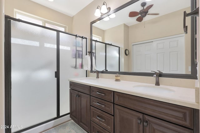 full bathroom with double vanity, a ceiling fan, a stall shower, and a sink