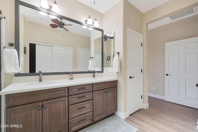 full bathroom with a sink, double vanity, visible vents, wood finished floors, and a ceiling fan