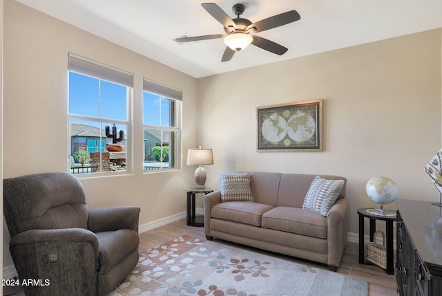living room featuring baseboards, a ceiling fan, and light wood-style flooring