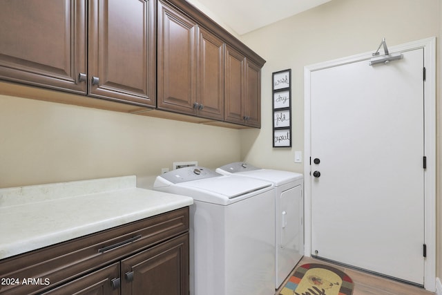 washroom with light hardwood / wood-style floors, cabinets, and washing machine and clothes dryer