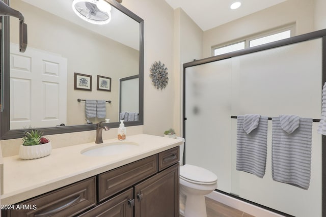 bathroom featuring toilet, a shower stall, wood finished floors, and vanity