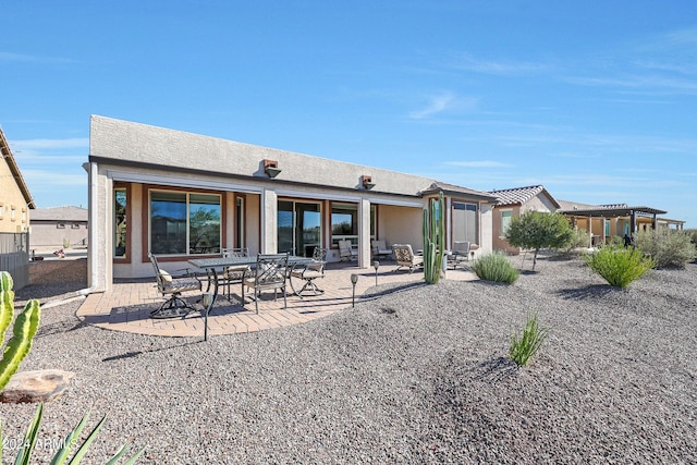 back of property with a patio and stucco siding