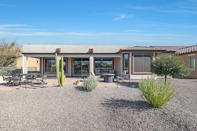 rear view of property featuring a patio, a fire pit, and fence
