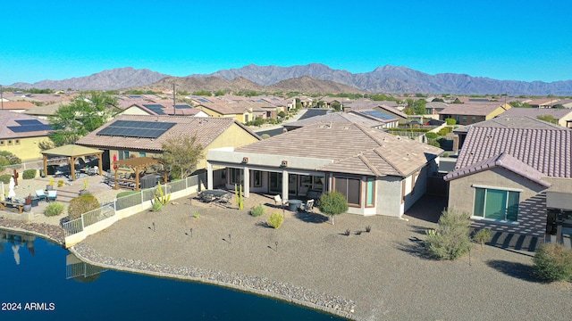 exterior space with a fenced backyard, stucco siding, a tiled roof, a residential view, and a water and mountain view