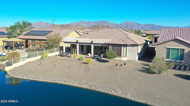 rear view of house featuring a patio, a tile roof, stucco siding, a water and mountain view, and a fenced backyard