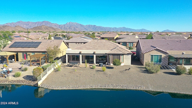 rear view of house with solar panels, a patio area, and a water and mountain view