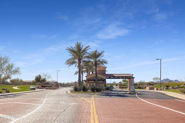 view of street featuring curbs, a gated entry, and street lighting