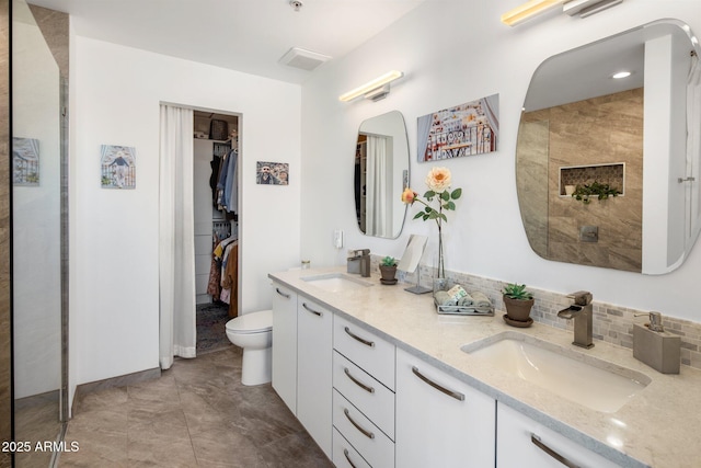 1 E Lexington Ave Unit 1209, Phoenix, AZ 85012 - bathroom with double vanity, a walk in closet, toilet, and decorative backsplash
