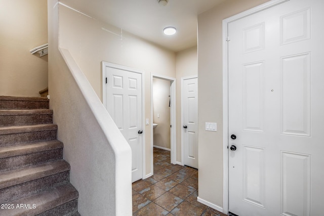 foyer with stairway, stone finish floor, and baseboards
