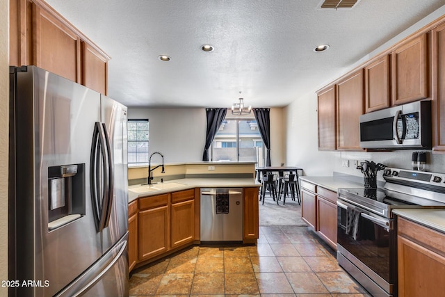 kitchen with a sink, light countertops, stainless steel appliances, and a peninsula