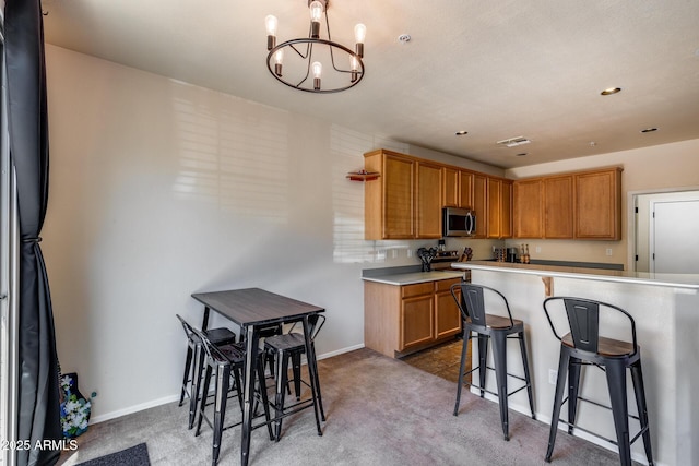 kitchen featuring a breakfast bar area, light colored carpet, light countertops, a chandelier, and stainless steel appliances