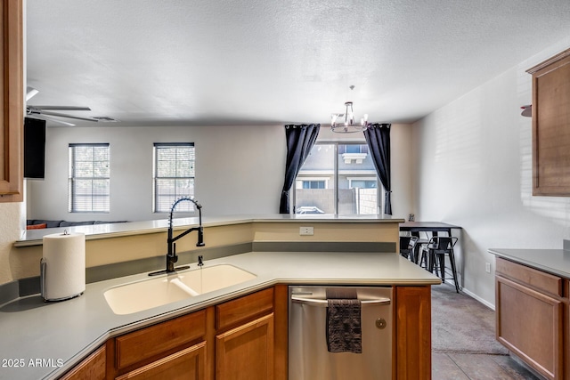 kitchen with a sink, dishwasher, and brown cabinets