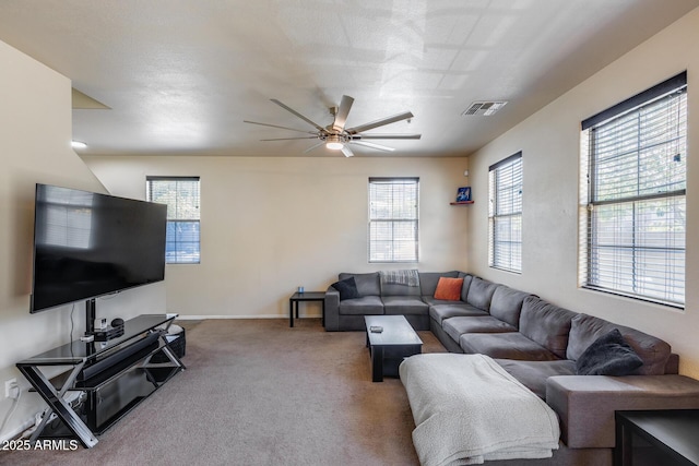 carpeted living area featuring baseboards, a ceiling fan, and visible vents