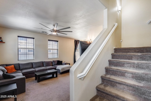 stairway with carpet floors, a ceiling fan, and visible vents