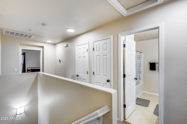 hall with baseboards, visible vents, and light floors