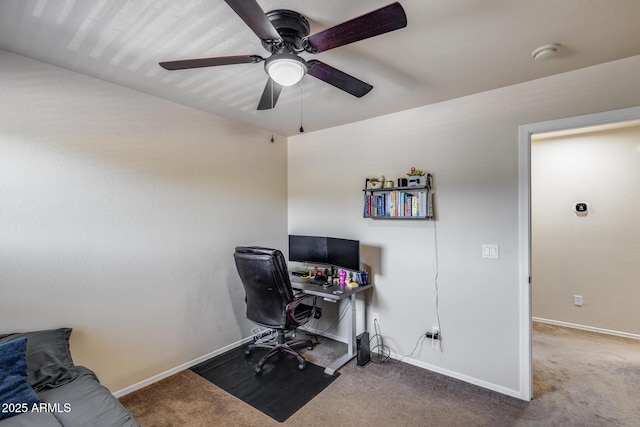carpeted home office with ceiling fan and baseboards