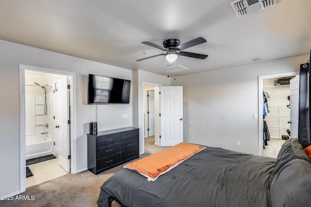 bedroom featuring ceiling fan, light colored carpet, a walk in closet, and visible vents