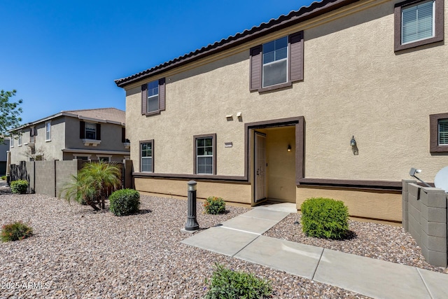 multi unit property with fence, stucco siding, and a tile roof