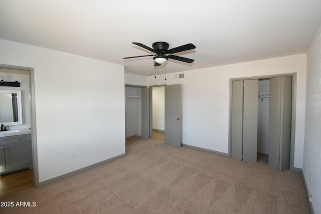 unfurnished bedroom with light carpet, sink, ceiling fan, and ensuite bathroom