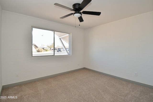 unfurnished room with carpet, ceiling fan, and brick wall