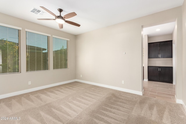 empty room with light colored carpet, plenty of natural light, and ceiling fan