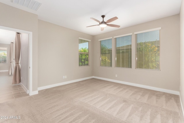 unfurnished room with ceiling fan, light carpet, and a wealth of natural light