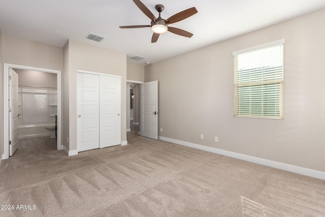 unfurnished bedroom with ensuite bathroom, ceiling fan, light colored carpet, and a closet