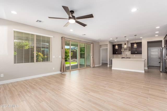 unfurnished living room featuring ceiling fan, light hardwood / wood-style floors, and sink