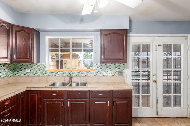 kitchen featuring light tile patterned floors, sink, backsplash, tile countertops, and french doors