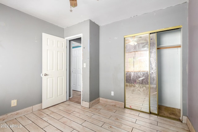 unfurnished bedroom with ceiling fan, a closet, and light wood-type flooring